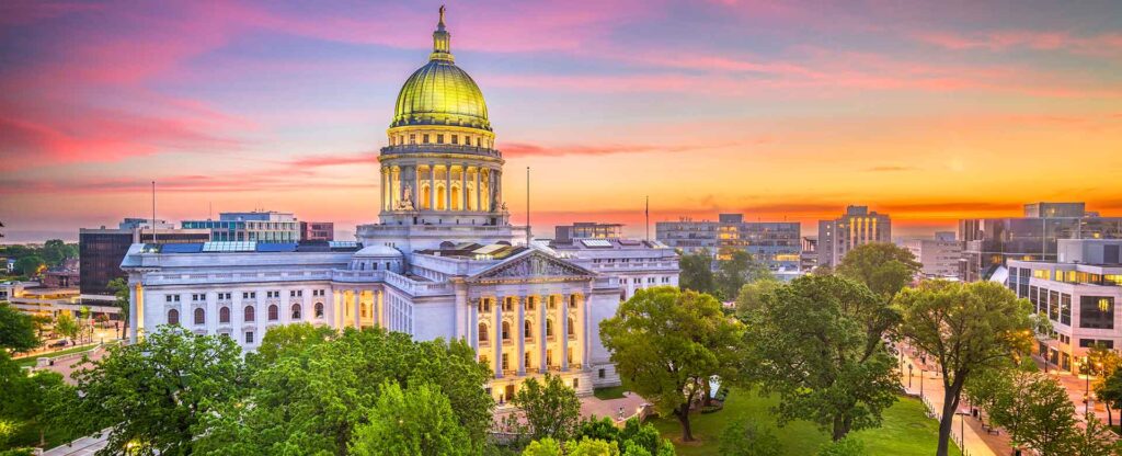 BPI Color Madison WI view of the Wisconsin State Capitol at sunset, surrounded by lush trees and city buildings in downtown Madison.
