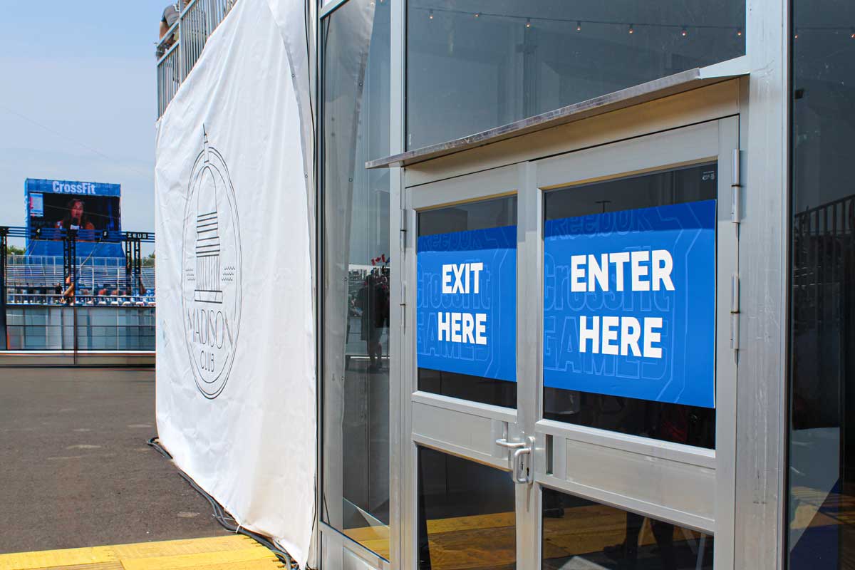 CrossFit Games Signage 10 Custom "EXIT HERE" signage displayed on exterior building doors. A large banner with a design for Madison, Wisconsin is hanging to the left.