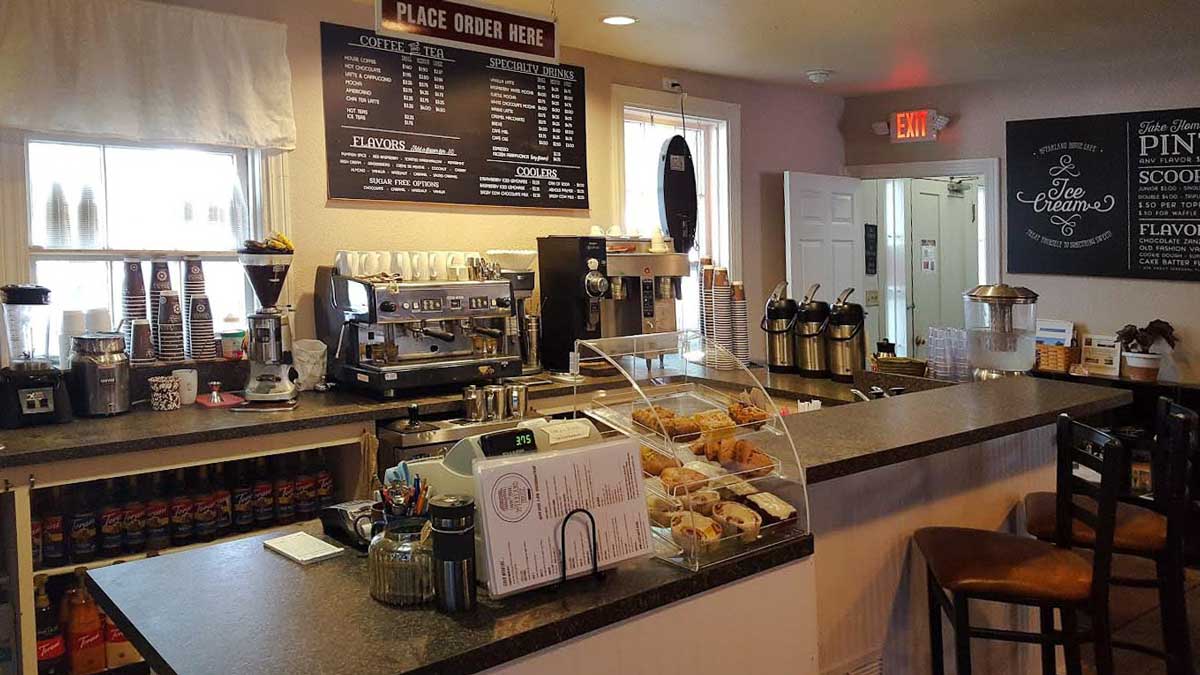 McFarland House Cafe 6 Front counter view of a coffee shop/ cafe, displaying two menu boards and a pastry cabinet.