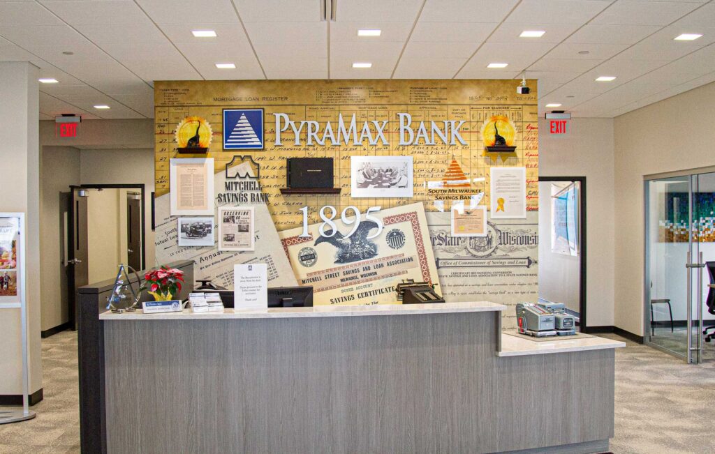 PyraMax Bank lobby wall installation with a dimensional timeline mural showcasing historic banking artifacts and logos.