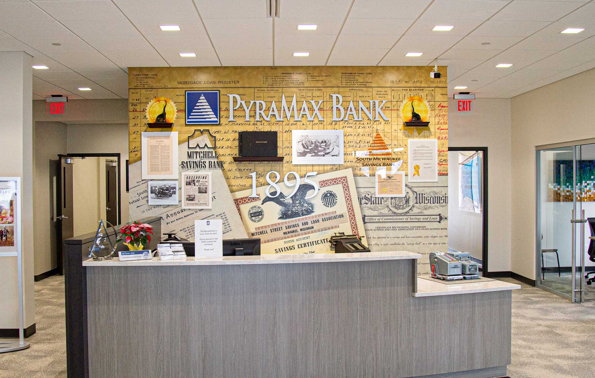 Portfolio Menu 18 PyraMax Bank lobby wall installation with a dimensional timeline mural showcasing historic banking artifacts and logos.