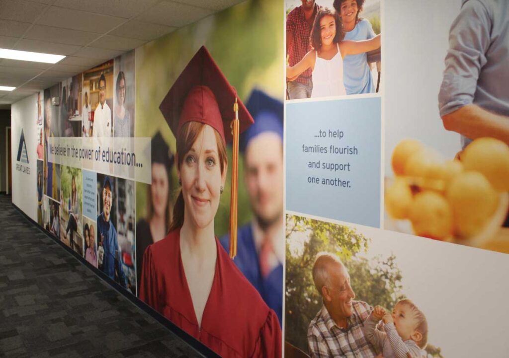 Great Lakes Wall Graphics 2 Large adhesive wall fabric that runs the length of a hallway with a custom graphic collage showing people in graduation caps and gowns.