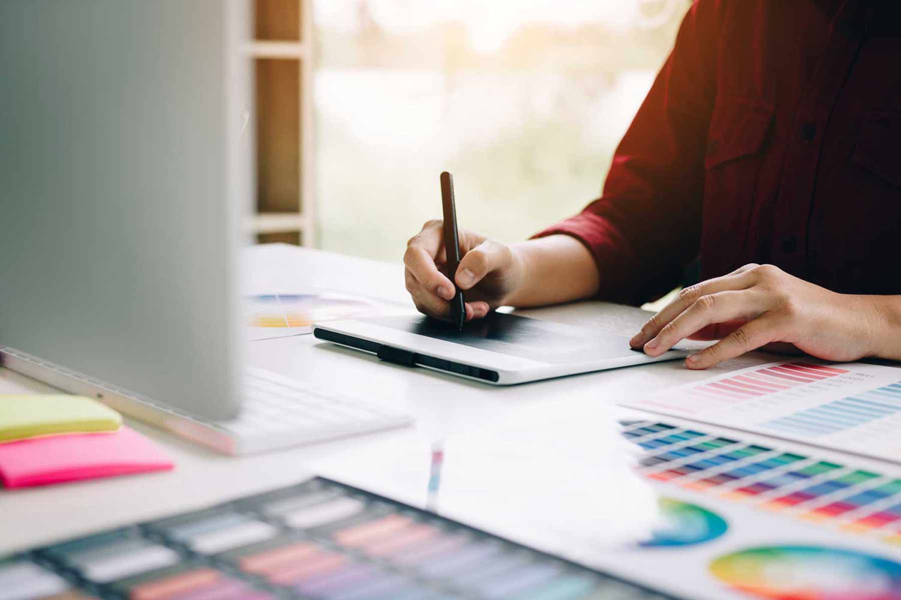 Person working at a desk, writing on a notepad.
