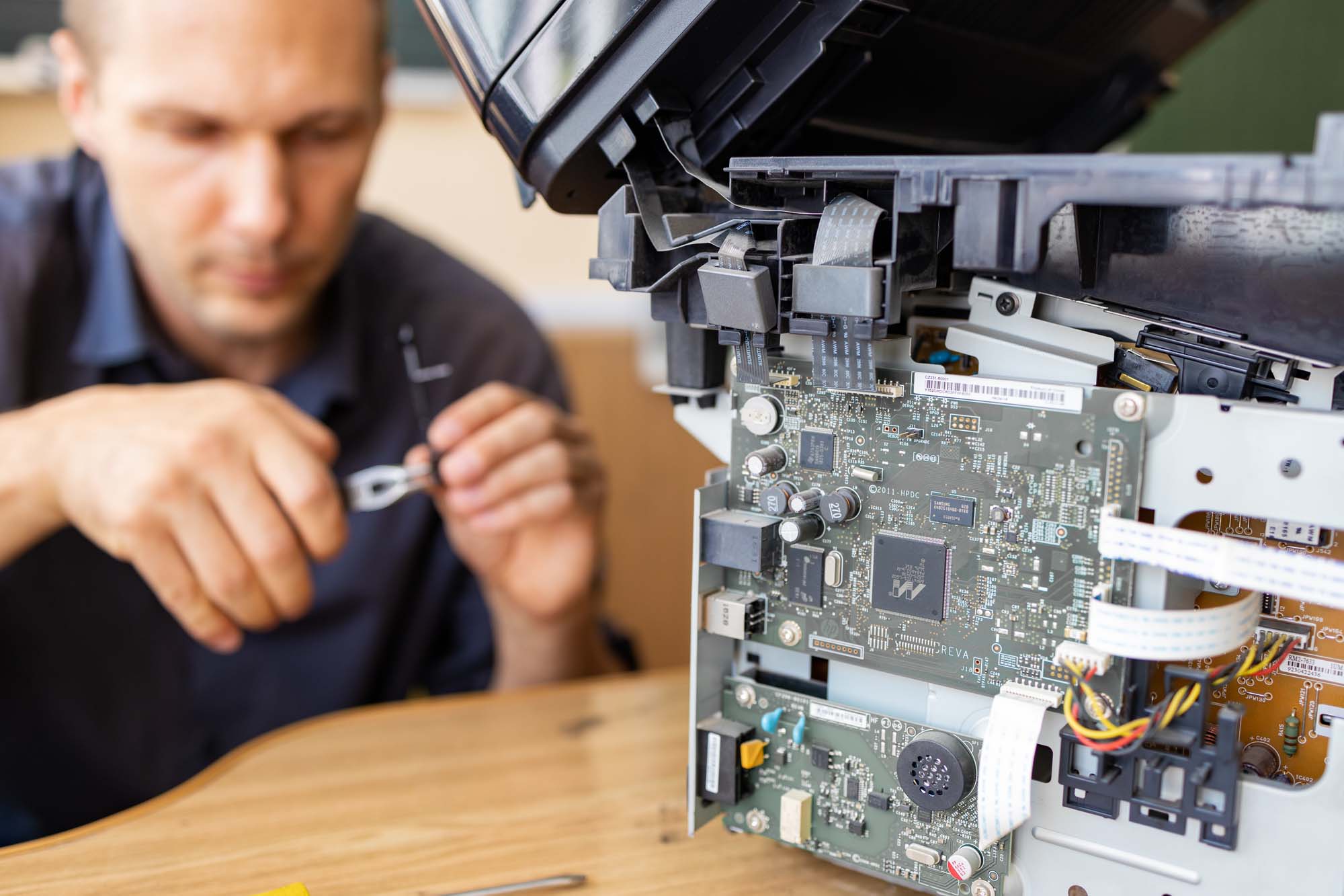 Printing Solutions Menu 7 Printer Repair – A technician working on the internal components of a printer, with the printer's circuit board exposed during a maintenance or diagnostic service.
