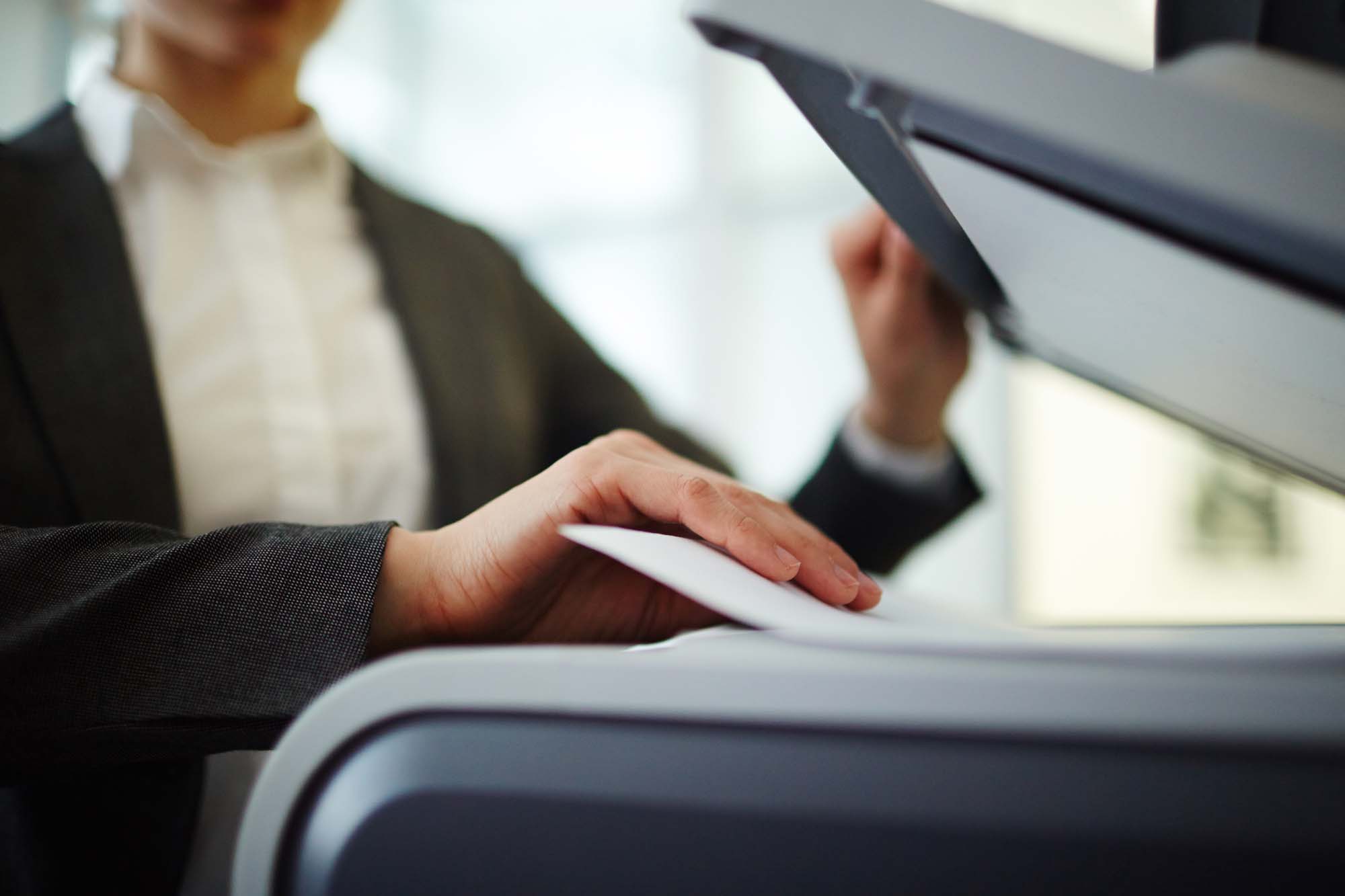 Professional Services Menu 4 Business Document Scanning image showing a person in business attire using a high-speed office scanner to digitize paper documents in a professional setting.