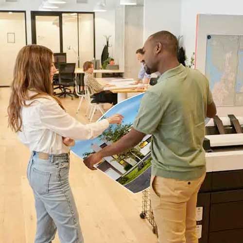 Used Printers 1 Two coworkers talking next to a printer.