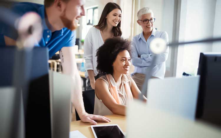 Team of coworkers looking at a computer screen together.