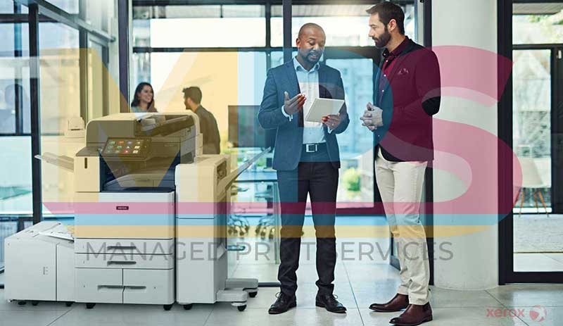 April 2025 Newsletter 22 Two men in suits standing near a Xerox printer.