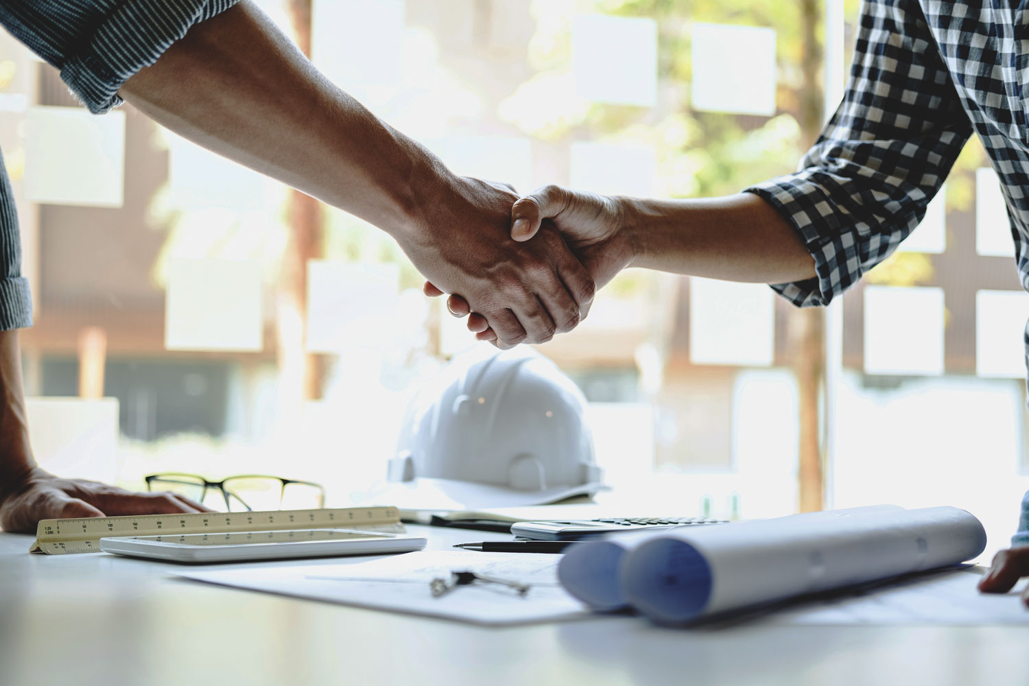 April 2025 Newsletter 9 Two people shaking hands over a work desk.