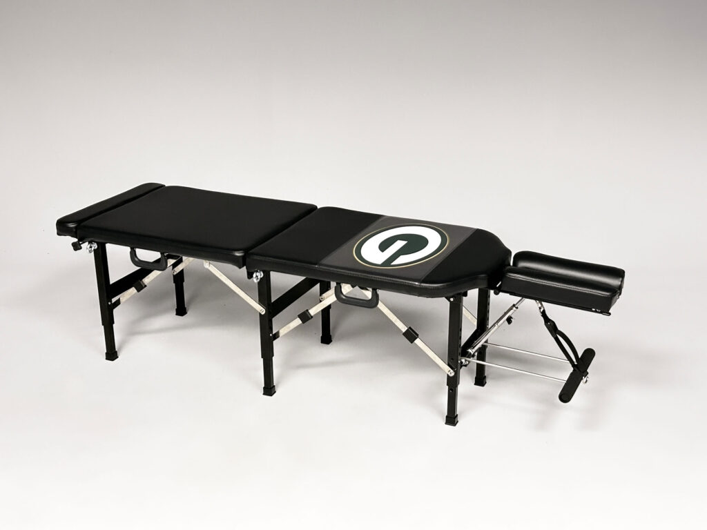 Thuli Tables custom black chiropractic table featuring the Green Bay Packers “G” logo, complete with adjustable headrest and foldable legs.