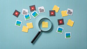 File Asset Management concept image showing a magnifying glass over a folder icon, surrounded by icons representing media files and documents.